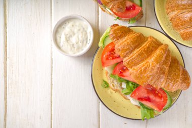 Taze sebzeli kruvasan sandviçi. Marul, domates, salatalık. Vitamin diyeti yaz veya bahar atıştırması, kahvaltı. Sarı arkaplan kopyalama alanı