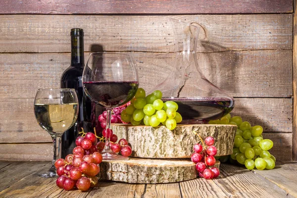 日差しと影のある赤と白のワインの眼鏡 ボトルとデカンター付き ブドウの束 有機台座と木製の背景に 秋の収穫 ワイナリーのコンセプト — ストック写真