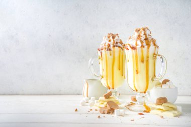 Ev yapımı Tuzlu Karamelli Eggnog veya Beyaz Sıcak Çikolatalı içecek, karamel soslu, krem şantili ve lokum, beyaz arka planda fotokopi alanı