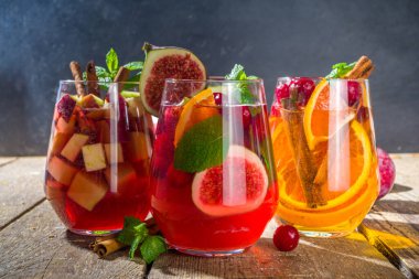Geleneksel sonbahar kış içkisi sıcak baharatlı sangria - kırmızı, pembe, beyaz. Elma şarabı, pembe kırmızı şarap, elma, portakal, nar, kızılcık, erik, incir, tarçın çubukları. Ahşap kırsal tablo kopyalama uzayı
