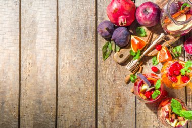 Geleneksel sonbahar kış içkisi sıcak baharatlı sangria - kırmızı, pembe, beyaz. Elma şarabı, pembe kırmızı şarap, elma, portakal, nar, kızılcık, erik, incir, tarçın çubukları. Ahşap kırsal tablo kopyalama uzayı