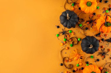 Parlak renkli Cadılar Bayramı parti aksesuarları ve dekor arka planı, renkli şekerler, geleneksel Cadılar Bayramı şekerlemeleri, balkabakları ve dekorasyonlar üst görünümde kopya alanı ile tatil ya da hile