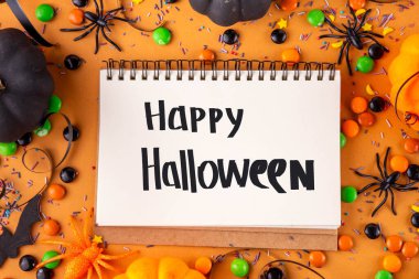 Parlak renkli Cadılar Bayramı parti aksesuarları ve dekor arka planı, renkli şekerler, geleneksel Cadılar Bayramı şekerlemeleri, balkabakları ve dekorasyonlar üst görünümde kopya alanı ile tatil ya da hile