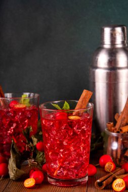 Sweet and sour fall seasonal alcohol hawthorn or rosehip cocktail, autumn berry mojito or margarita, spicy alcoholic drink with hawthorn or rosehip liquor, cinnamon, int crushed ice