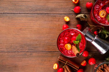 Sweet and sour fall seasonal alcohol hawthorn or rosehip cocktail, autumn berry mojito or margarita, spicy alcoholic drink with hawthorn or rosehip liquor, cinnamon, int crushed ice