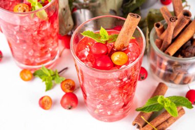 Sweet and sour fall seasonal alcohol hawthorn or rosehip cocktail, autumn berry mojito or margarita, spicy alcoholic drink with hawthorn or rosehip liquor, cinnamon, int crushed ice