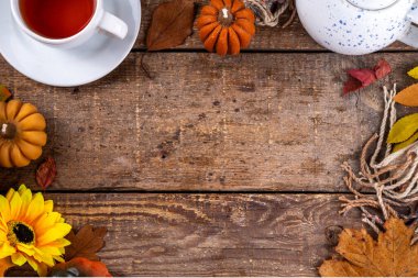 Sonbahar mevsiminde sıcak kahvaltı, bahçede erken sonbahar çayı, balkabağı mumları ve dekorlu taze demlenmiş çay fincanı, sonbahar yaprakları ve açık kitap, okuma zamanı sakin hayat