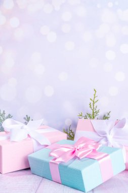 Pastel Noel arkaplanı mavi ve pembe hediyelerle donatılmış, çam ağacı dalları hafif karlı şenlik ışıkları bulanık arka plan fotokopi alanı