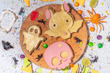 Funny halloween sandwiches. Set of various decorated symbols sandwich - bat, skull, ghost, with cucumber, cheese and meat sausages, white table background with Halloween decorations