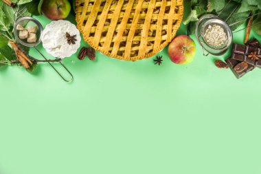 Sonbaharda elmalı turtayla pişirme arka planı. Geleneksel Amerikan elmalı turtası taze elmalar, tarçın, baharatlar, fırın malzemeleri, açık yeşil arka planda üst görünüm kopyalama alanı