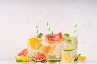 Yaz turunçgilleri arınma suyu, limon, limon, greyfurt, portakal, limonata, ahşap arka planda buzlu limonata içecekler. Buzlu mevsimlik içecek, meyve dilimleri ve naneli.