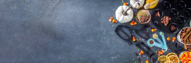 Halloween Gingerbread Cookies cooking background. Autumn holiday baking concept, ingredients, spices, halloween symbol cookie cutters - pumpkin, ghost, bat, witch hat, top view black table copy space
