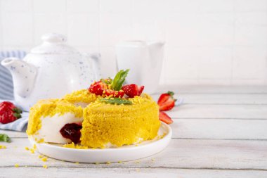 Tepetaklak Pasta yok, klasik Cheesecake New York 'un viral modası altın kurabiye parçacıkları, beyaz krem peynir ve böğürtlen reçeli katmanları, taze çilek ve ahşap masa üzerinde nane