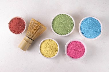 Beyaz kasede kurutulmuş kibrit tozu seti. Çeşitli renkler ve özetler eşleşiyor - yeşil, sarı, pembe, kırmızı, beyaz arka planda meyveli sağlıklı eşleşen çay içecekleri yapmak için.