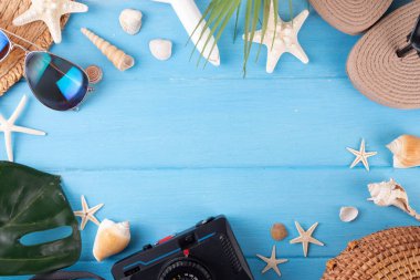Yaz tatili ve hasır şapkalı, çantalı, terlikli, palmiye yapraklı, güneş gözlüklü, kameralı, deniz kabuklu ve okyanus yıldızlı tatil geçmişi. Plaj ve tropikal yaz tatili arka planı, üst görünüm kopyalama alanı