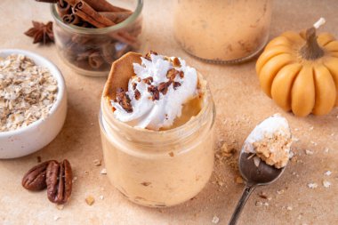 Kremalı, fındıklı ve krakerli yulaf ezmeli balkabağı turtası. Lezzetli kremalı balkabağı baharatlı yulaf, bej arka planda baharat ve dekoratif balkabakları, kopyalama alanı