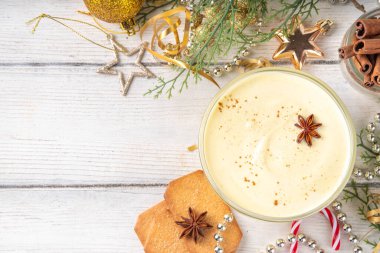 Noel kahvaltısı, Eggnog Yunan yoğurdu. Bir kase yoğurt, yumurta sarısı, hindistan cevizi, vanilya ve baharatla çırpılmış, Noel süslemeli arka planda. Lezzetli, protein açısından zengin sağlıklı eggnog versiyonu.