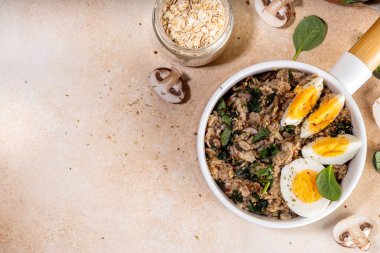 Lezzetli bir gecelik yulaf ezmesi. Ispanaklı, mantarlı ve yumurtalı lezzetli, şekersiz kahvaltı yulafları. Pişirmek için bej arka plan malzemeleri.