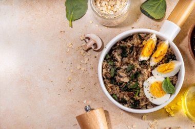 Lezzetli bir gecelik yulaf ezmesi. Ispanaklı, mantarlı ve yumurtalı lezzetli, şekersiz kahvaltı yulafları. Pişirmek için bej arka plan malzemeleri.