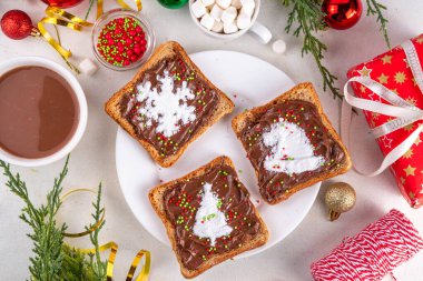 Çocuklar için Noel kahvaltısı, yaratıcı tost ekmeği sandviçleri. Ev yapımı Noel sandviçleri çikolata ezmesi, fıstık ezmesi, lokum ve şeker tozuyla yapılır.