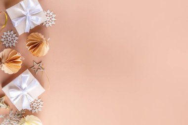 Pastel rengi altın bej Noel ve yeni yıl arkaplanı. Kış bayramı kutlamaları. Çeşitli Noel ağacı altın topları, mücevherler, yıldızlar, kar taneleri, pastel arka planda hediye kutuları.