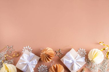 Pastel rengi altın bej Noel ve yeni yıl arkaplanı. Kış bayramı kutlamaları. Çeşitli Noel ağacı altın topları, mücevherler, yıldızlar, kar taneleri, pastel arka planda hediye kutuları.