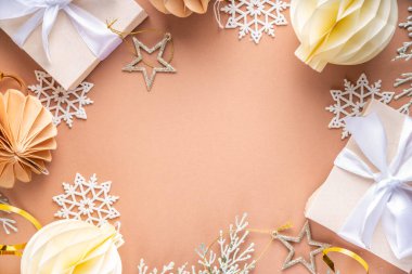 Pastel rengi altın bej Noel ve yeni yıl arkaplanı. Kış bayramı kutlamaları. Çeşitli Noel ağacı altın topları, mücevherler, yıldızlar, kar taneleri, pastel arka planda hediye kutuları.