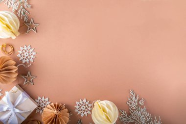 Pastel rengi altın bej Noel ve yeni yıl arkaplanı. Kış bayramı kutlamaları. Çeşitli Noel ağacı altın topları, mücevherler, yıldızlar, kar taneleri, pastel arka planda hediye kutuları.