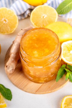 Zencefilli limonlu reçelli marmelat, beyaz masa fotokopi alanında taze zencefil, limon ve nane içeren küçük kavanozda saklanır.