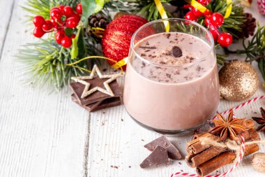 Baharatlı çikolatalı eggnog kokteyli, tarçın çubuğu, hindistan cevizi ve çikolata serpiştirilmiş, samimi bir Noel arkaplanı. 
