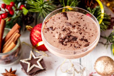 Baharatlı çikolatalı eggnog martini kokteyli, tarçın çubuğu, hindistan cevizi ve çikolata serpiştirilmiş, samimi bir Noel arkaplanı. 