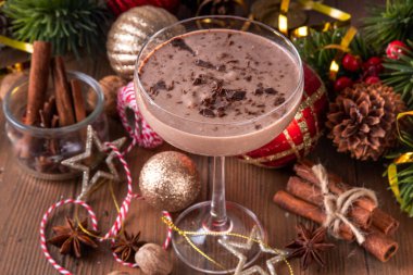 Baharatlı çikolatalı eggnog martini kokteyli, tarçın çubuğu, hindistan cevizi ve çikolata serpiştirilmiş, samimi bir Noel arkaplanı. 