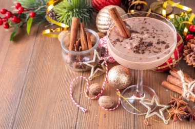 Baharatlı çikolatalı eggnog martini kokteyli, tarçın çubuğu, hindistan cevizi ve çikolata serpiştirilmiş, samimi bir Noel arkaplanı. 