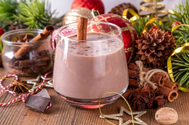 Baharatlı çikolatalı eggnog kokteyli, tarçın çubuğu, hindistan cevizi ve çikolata serpiştirilmiş, samimi bir Noel arkaplanı. 
