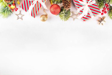 Noel ve Yeni Yıl kutlamaları sınırına sahip beyaz arka planda hediye kutuları, Noel ağacı dalları, dekorasyonlar ve tatil mücevherleri yer alıyor