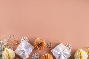 Pastel rengi altın bej Noel ve yeni yıl arkaplanı. Kış bayramı kutlamaları. Çeşitli Noel ağacı altın topları, mücevherler, yıldızlar, kar taneleri, pastel arka planda hediye kutuları.
