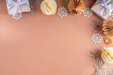 Pastel rengi altın bej Noel ve yeni yıl arkaplanı. Kış bayramı kutlamaları. Çeşitli Noel ağacı altın topları, mücevherler, yıldızlar, kar taneleri, pastel arka planda hediye kutuları.