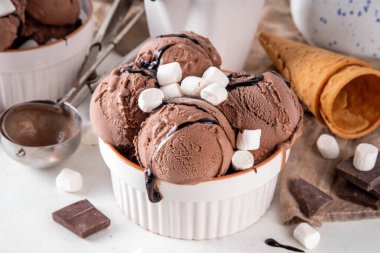 Koyu çikolata soslu sıcak çikolata dondurması ve lokum. Beyaz kasede çikolatalı dondurma, üzerine çikolata serpiştirilmiş beyaz mutfak masasında fotokopi alanı.