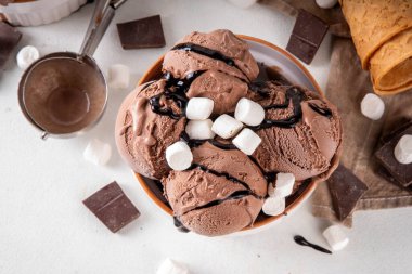 Koyu çikolata soslu sıcak çikolata dondurması ve lokum. Beyaz kasede çikolatalı dondurma, üzerine çikolata serpiştirilmiş beyaz mutfak masasında fotokopi alanı.
