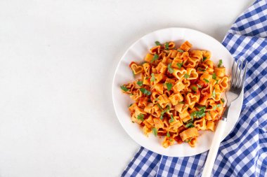 Kalp şeklinde domates soslu makarna. Klasik İtalyan salamura soslu makarna ya da taze otlu bolonez makarna. Sevgililer günü ya da randevu gecesi için basit ve lezzetli bir tarif. Beyaz masa fotokopisinde.