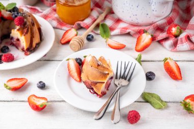 Taze meyve ve böğürtlenli yaz pastası. Geleneksel yuvarlak sünger keki, çilekli mevsimlik tatlı, ahududu, yabanmersini, bal ve şeker serpintileri, beyaz ahşap masa fotokopisi alanı