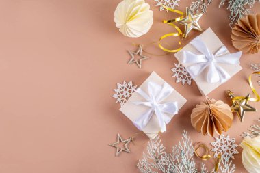 Pastel rengi altın bej Noel ve yeni yıl arkaplanı. Kış bayramı kutlamaları. Çeşitli Noel ağacı altın topları, mücevherler, yıldızlar, kar taneleri, pastel arka planda hediye kutuları.