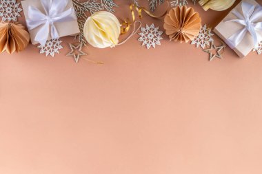 Pastel rengi altın bej Noel ve yeni yıl arkaplanı. Kış bayramı kutlamaları. Çeşitli Noel ağacı altın topları, mücevherler, yıldızlar, kar taneleri, pastel arka planda hediye kutuları.