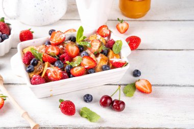 Yaz meyvesi ve Fransız tostu fırınlanmış güveç. Ev yapımı lezzetli Fransız tostu, kremalı kahvaltı pastası, kızarmış ekmek ve taze çilek, yabanmersini, ahududu ve kirazlı.