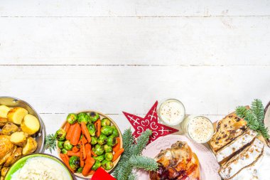 Geleneksel yemekli Noel yemeği masası ve fırında jambon, tavuk, kızarmış havuç ve Brüksel lahanası, patates, Noel dekoru.