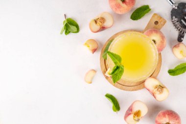 Düz şeftalili martini ya da margarita limonata soğuk meyve suyu, nane ve limonlu yaz meyve suyu kokteyli, beyaz masada.