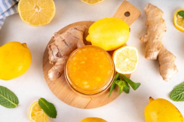 Zencefilli limonlu reçelli marmelat, beyaz masa fotokopi alanında taze zencefil, limon ve nane içeren küçük kavanozda saklanır.