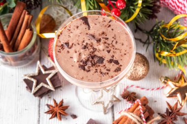 Baharatlı çikolatalı eggnog martini kokteyli, tarçın çubuğu, hindistan cevizi ve çikolata serpiştirilmiş, samimi bir Noel arkaplanı.