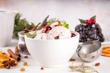 Noel pudingli dondurma, kış ve Noel geleneksel aromalı beyaz vanilyalı dondurma puding, alkol şurubu, çikolata parçaları ile karıştırılmış beyaz masa üzerinde Noel süsü ve İngiliz pudingi.