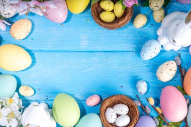 İlkbahar Paskalya bayramı üst manzaralı düz arka planda yumurtalar, tavşanlar ve bahar çiçekleri yatar. Kopya alanı olan parlak renkli tebrik kartı arkaplanı.